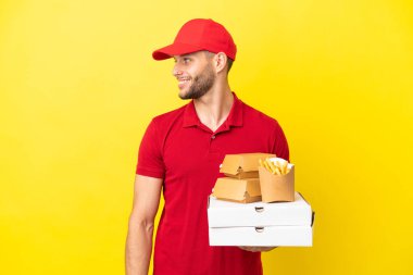 Pizza teslimatçısı, izole edilmiş arka planda pizza kutuları ve hamburgerleri alıyor.