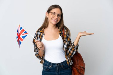 Young Lithuanian woman holding an United Kingdom flag isolated on white background holding copyspace imaginary on the palm to insert an ad