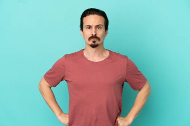 Kafkasyalı genç adam mavi arka planda izole edilmiş kızgın.