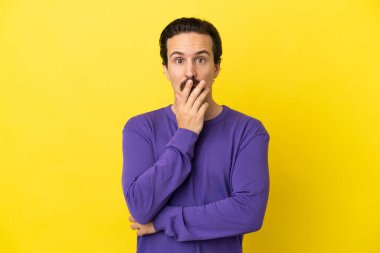 Sarı arka planda izole edilmiş genç beyaz adam sağa bakarken şaşırdı ve şok oldu.