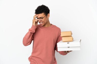 Beyaz arka planda izole edilmiş hamburger ve pizzalar tutan genç Afrikalı Amerikalı adam gülüyor.