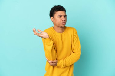 Genç Afrikalı Amerikalı bir adam mavi arka planda izole edilmiş.