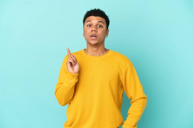 Genç Afro-Amerikalı adam mavi arka planda izole edildi. Çözümü bulmak için parmağını kaldırdı.