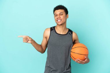 Basketball player African American man isolated on blue background pointing finger to the side