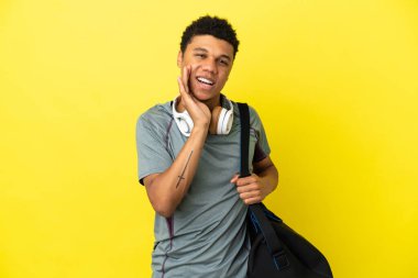 Young sport African American man with sport bag isolated on yellow background shouting with mouth wide open