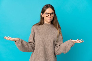 Genç Litvanyalı kadın mavi arka planda izole edilmiş. Şüpheleri var.