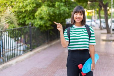 Genç esmer kadın açık havada paten kayıyor ve yan tarafı gösteriyor.