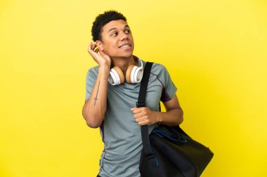 Young sport African American man with sport bag isolated on yellow background thinking an idea