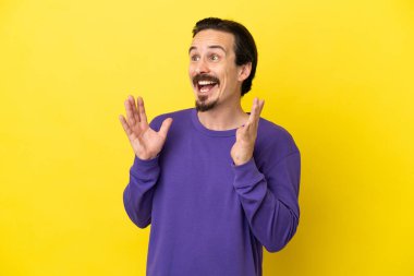 Sarı arka planda yalıtılmış beyaz bir adam. Şaşırtıcı bir yüz ifadesi var.