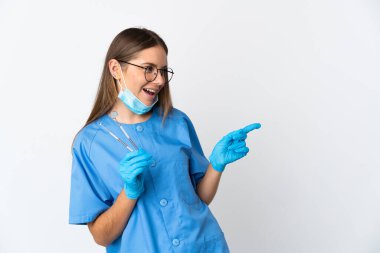 Lithuanian woman dentist holding tools over isolated background pointing finger to the side and presenting a product