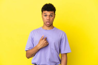 Sarı arka planda izole edilmiş genç Afrikalı Amerikalı bir adam kendini işaret ediyor.