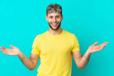 Yüzünde şok ifadesi olan, mavi arka planda izole edilmiş, yakışıklı beyaz bir adam.