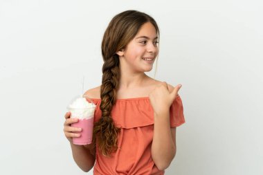Beyaz arka planda izole edilmiş çilekli milkshake 'li küçük beyaz kız bir ürün sunmak için kenarı işaret ediyor.