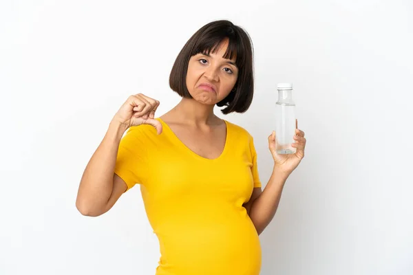 白い背景に孤立した水のボトルを持っている若い妊婦は否定的な表現で親指を下に示す — ストック写真