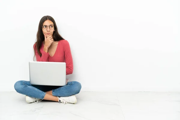 一个年轻的法国姑娘坐在地板上 膝上型电脑里充满了疑虑和困惑的表情 — 图库照片