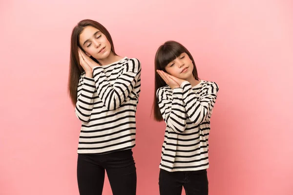 Hermanitas Aisladas Sobre Fondo Rosa Haciendo Gesto Sueño Expresión Dorable —  Fotos de Stock