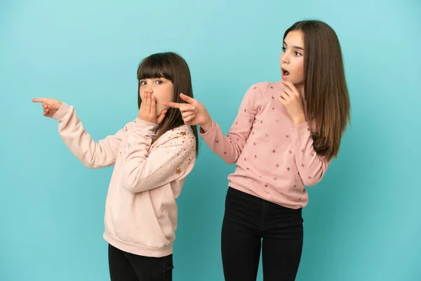 Små Systrar Flickor Isolerade Blå Bakgrund Pekar Finger Sidan Med — Stockfoto