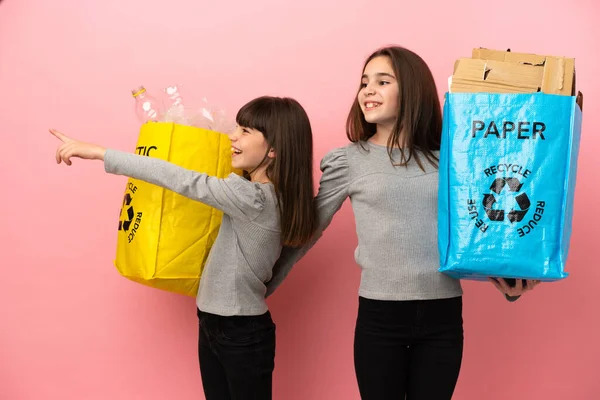 Küçük Kız Kardeşler Geri Dönüşüm Kağıdı Plastiği Pembe Arka Planda — Stok fotoğraf