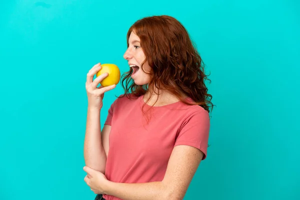 Teenager Rotschopf Mädchen Isoliert Auf Blauem Hintergrund Essen Einen Apfel — Stockfoto