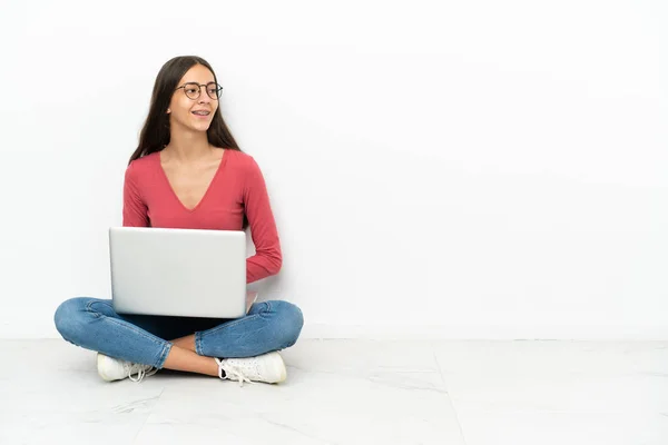 年轻的法国姑娘坐在地板上 手提电脑在旁边看 — 图库照片