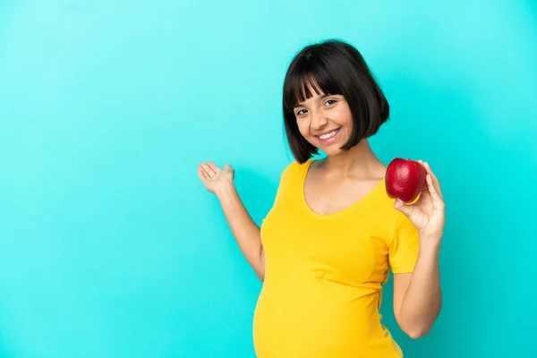 妊娠中の女性青の背景に手を伸ばしに隔離されたリンゴを持っている側に来て招待するために — ストック写真