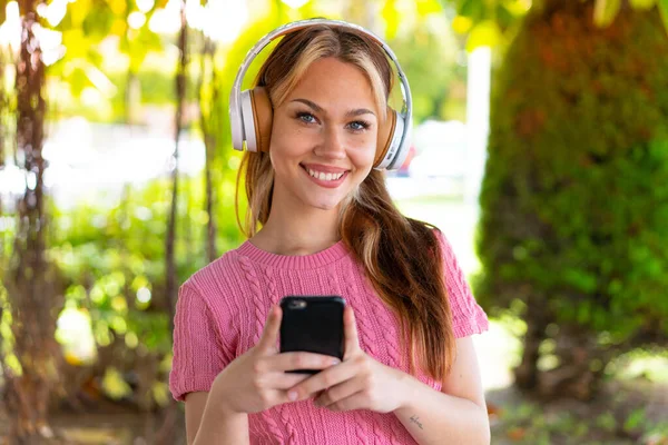 Joven Mujer Bonita Aire Libre Escuchando Música Con Móvil Mirando — Foto de Stock