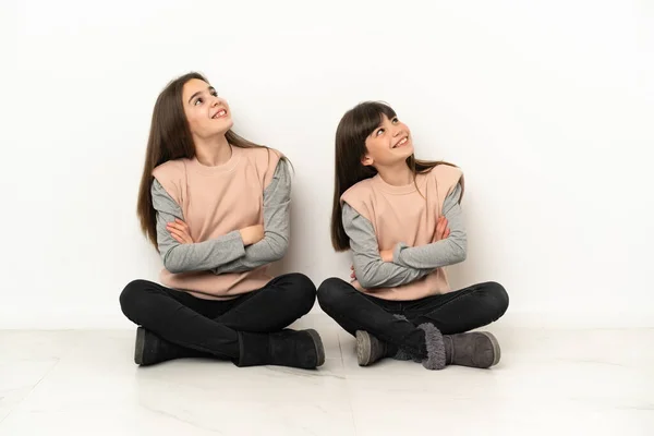 Hermanitas Sentadas Suelo Aisladas Sobre Fondo Blanco Mirando Hacia Arriba —  Fotos de Stock