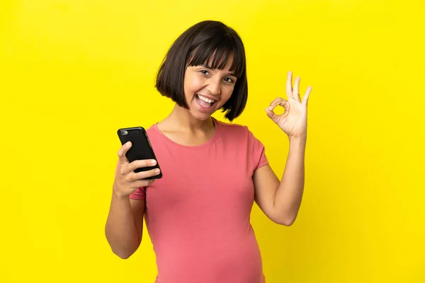 Young Mixed Race Pregnant Woman Isolated Yellow Background Using Mobile — Stock Fotó