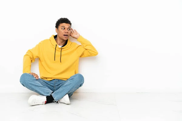 Young African American Man Sitting Floor Isolated White Background Listening — Foto Stock