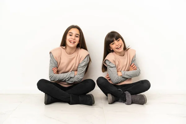 Irmãzinhas Sentadas Chão Isoladas Fundo Branco Mantendo Braços Cruzados Enquanto — Fotografia de Stock