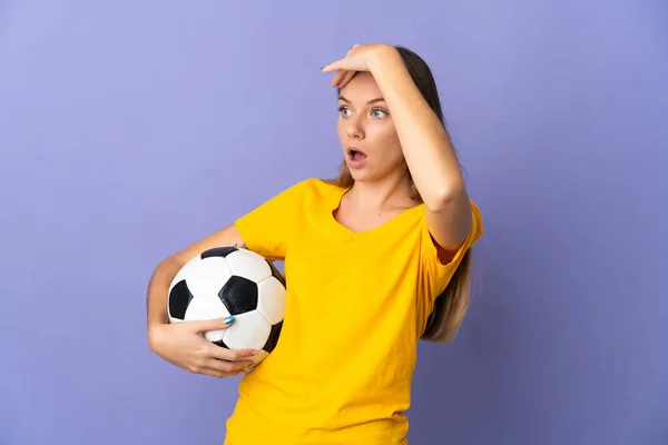 年轻的立陶宛足球女运动员被隔离在紫色背景下 一边看一边惊讶地做着手势 — 图库照片