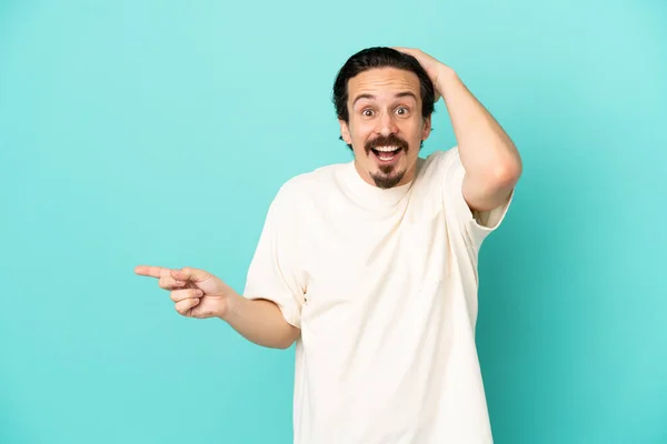 Joven Hombre Caucásico Aislado Sobre Fondo Azul Sorprendido Señalando Dedo — Foto de Stock