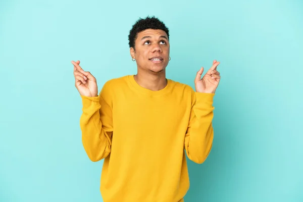 Joven Afroamericano Aislado Sobre Fondo Azul Con Dedos Cruzando Deseando — Foto de Stock