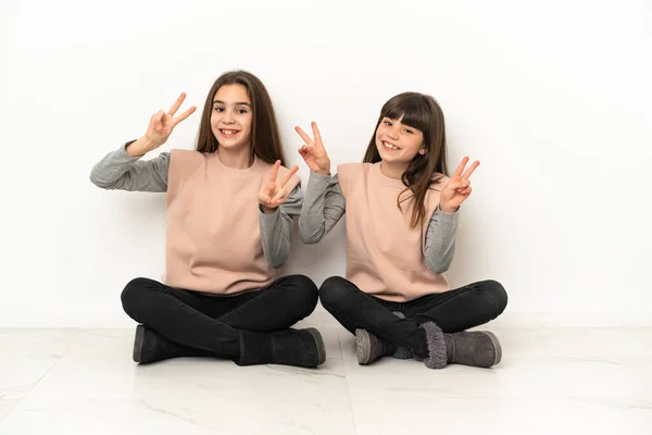 Hermanitas Sentadas Suelo Aisladas Sobre Fondo Blanco Sonriendo Mostrando Signo —  Fotos de Stock