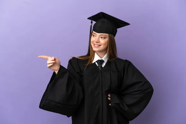 Joven Graduado Universitario Sobre Fondo Púrpura Aislado Señalando Dedo Hacia — Foto de Stock