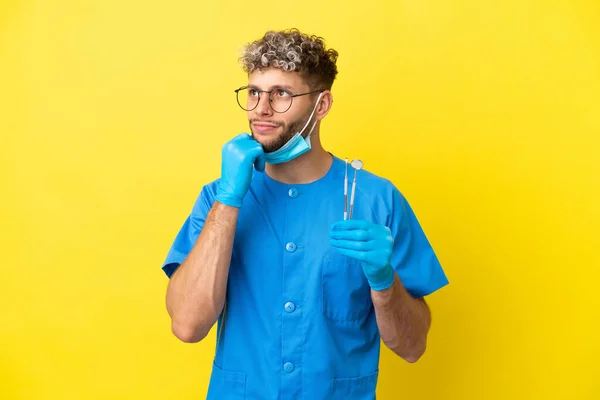 Dentysta Biały Mężczyzna Trzyma Narzędzia Izolowane Żółtym Tle Patrząc Górę — Zdjęcie stockowe