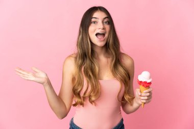 Kornet dondurması olan beyaz bir kadın pembe arka planda izole edilmiş, şok olmuş bir yüz ifadesi var.