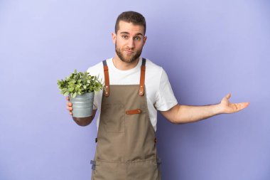 Bahçıvan Kafkasyalı bir adam sarı arka planda bir bitki tutuyor. Kuşkuları var ve el kaldırıyor.