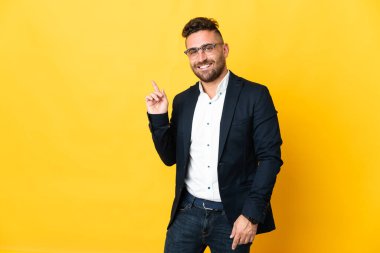 İzole edilmiş sarı arka planda bir iş adamı parmak işareti yapıyor.