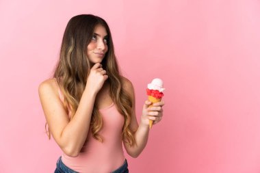 Kornet dondurması olan beyaz bir kadın pembe arka planda izole edilmiş ve yukarı bakıyor.