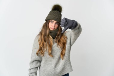 Beyaz arka planda izole edilmiş beyaz şapkalı beyaz kadın olumsuz bir ifadeyle baş parmağını aşağı gösteriyor.