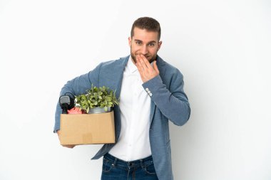 Beyaz arka planda izole edilmiş şeylerle dolu bir kutuyu alırken genç beyaz tenli hareketler yapıyor. Mutlu ve gülümseyen ağızlarını eliyle kapatıyor.