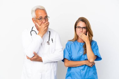 Orta yaşlı doktor ve hemşire beyaz arka planda izole edilmiş ağızlarını uygunsuz bir şey söylediği için elleriyle kapatmış.