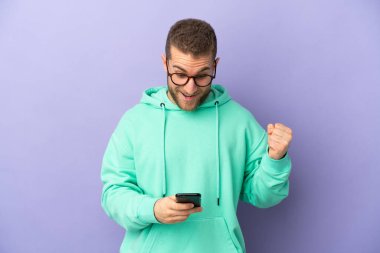 Mor arka planda izole edilmiş yakışıklı beyaz adam şaşırdı ve bir mesaj gönderiyor.