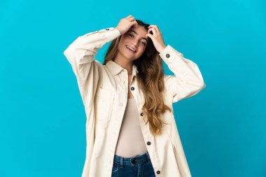 Mavi arka planda izole edilmiş genç beyaz kadın gülüyor.