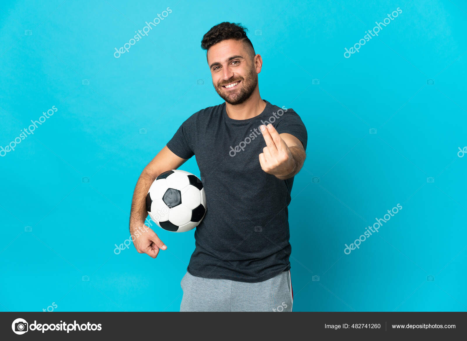 Jogador de futebol forte com bola de futebol e sorrindo em fundo branco  isolado