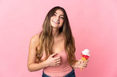 Kornet dondurması olan beyaz bir kadın pembe arka planda izole edilmiş, gülümsüyor.