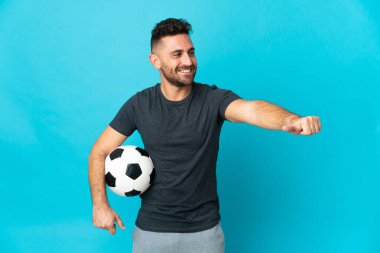 Futbolcu mavi zemin üzerinde izole edilmiş bir şekilde baş parmak hareketi yapıyor