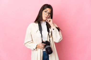 Genç fotoğrafçı Brezilyalı kız pembe arka planda izole edilmiş bir fikir düşünüyor.