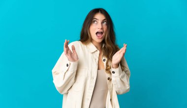 Mavi arka planda yalıtılmış beyaz bir kadın. Şaşırtıcı bir yüz ifadesi var.